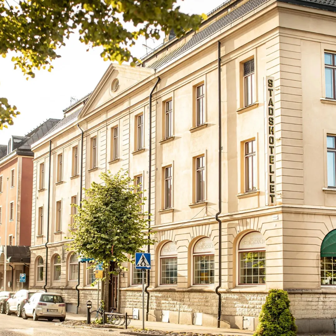 Hotellets ljusa stenfasad med en hög vertikal skylt