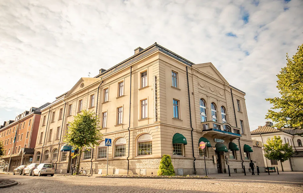 Hotellet sett från gatan, en ljus stenbyggnad med gröna markiser under en molnig himmel