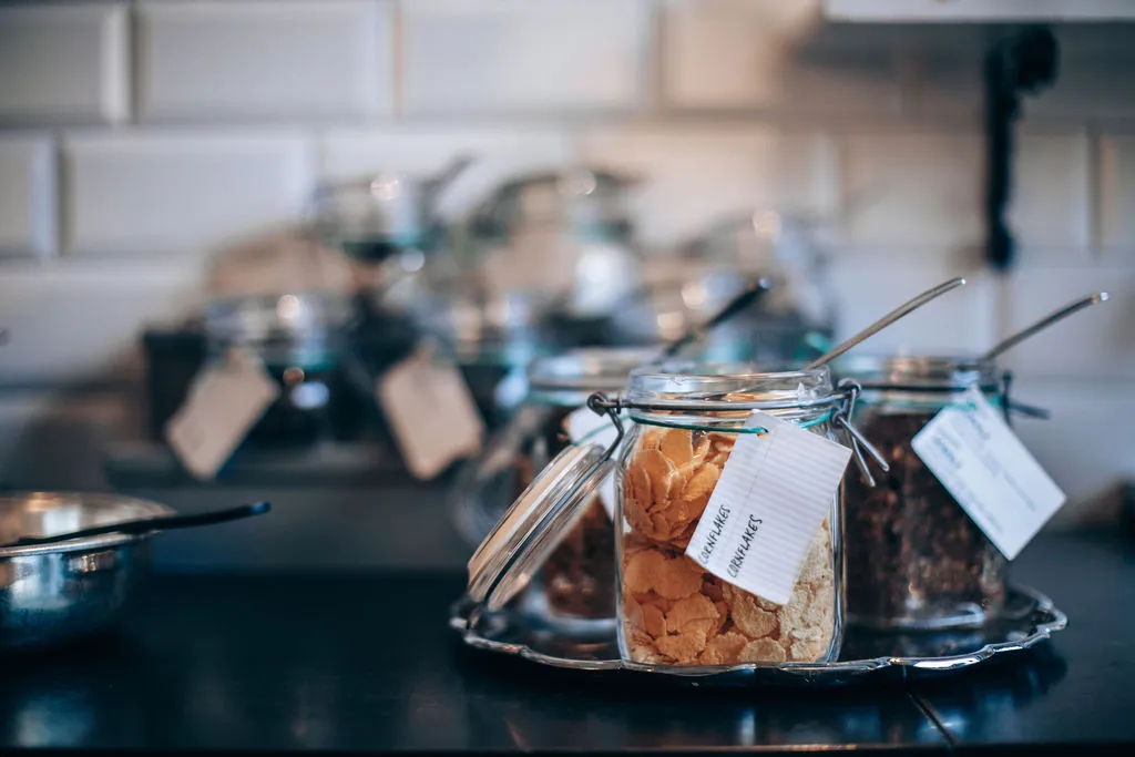 Glasburkar med flingor och granola på ett silverfat