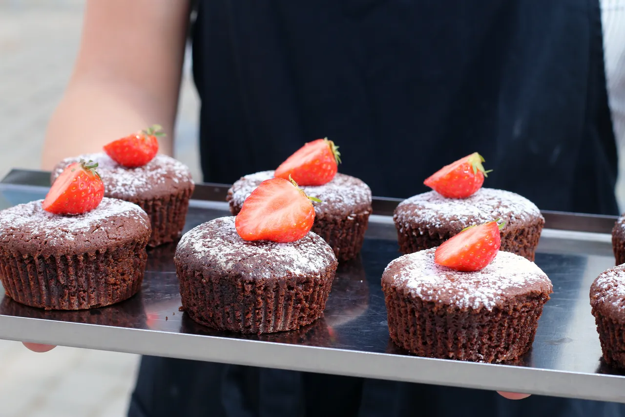Bricka med chokladmuffins toppade med florsocker och färska jordgubbar