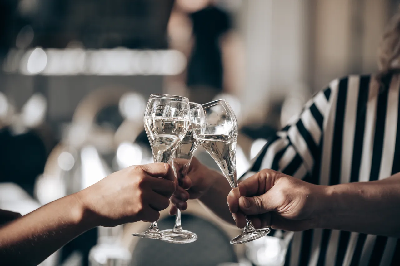 Två händer skålar med glas i mousserande vin