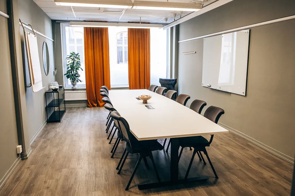 Mötesrum med långbord, whiteboards och orange gardiner