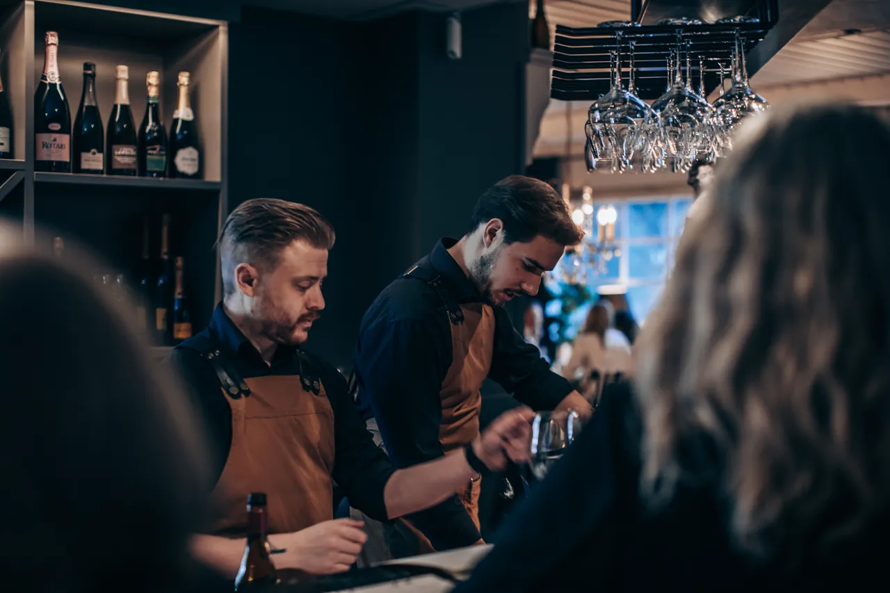 Bartendrar i förkläden bakom baren i vinbaren