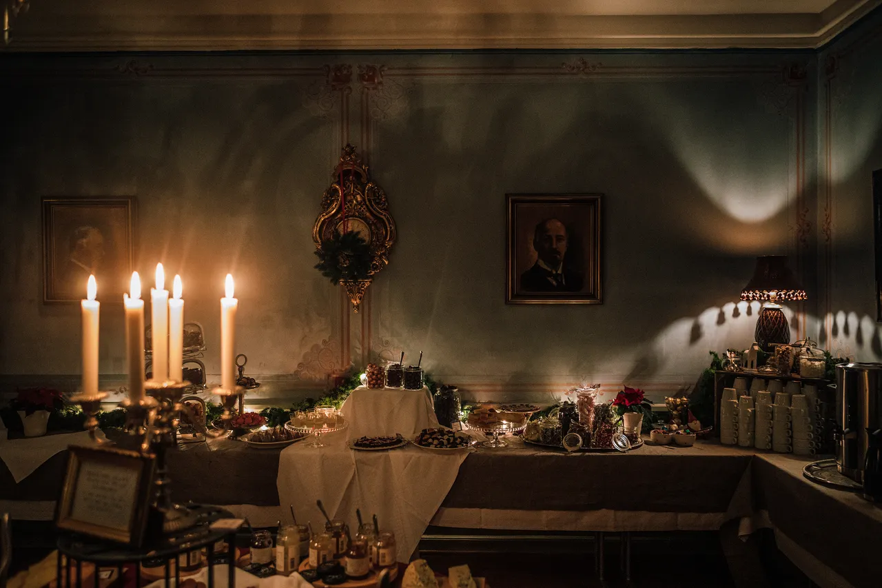 Julbord i levande ljus i en mörkgrön herrgårdssal