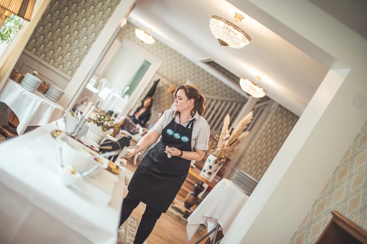 Servitris i förkläde vid buffén i en ljus salong med kristallkronor