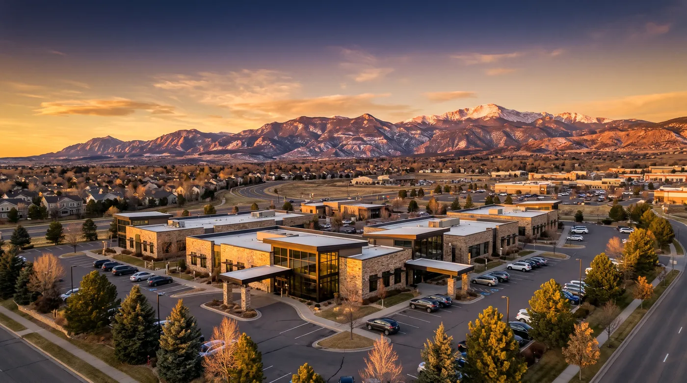Golden-hour aerial of a modern medical and dental office park with mountains behind