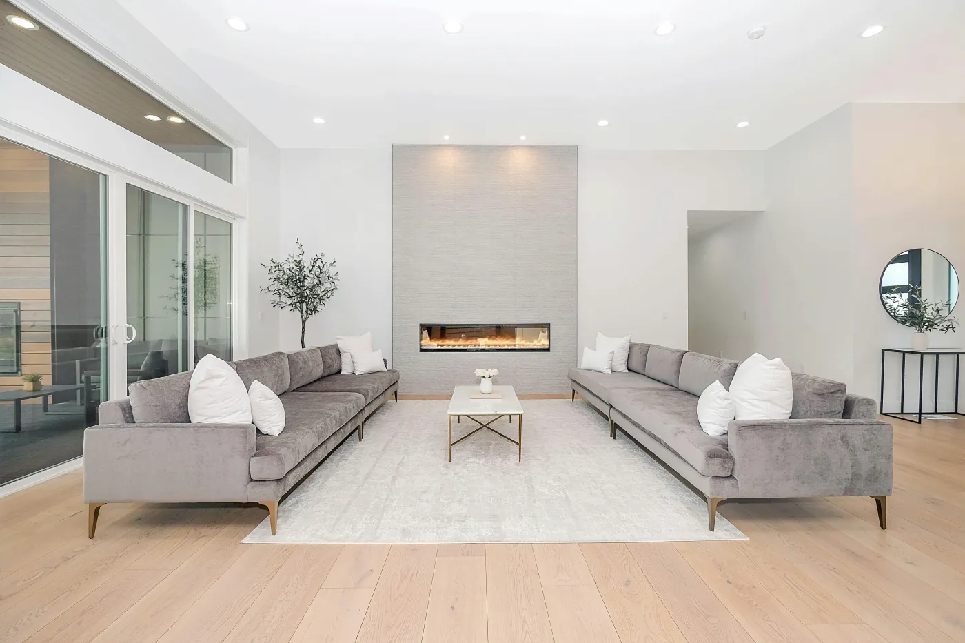 Bright living room with grey velvet sofas, a linear fireplace, and pale oak floors Bright living room with grey velvet sofas, a linear fireplace, and pale oak floors