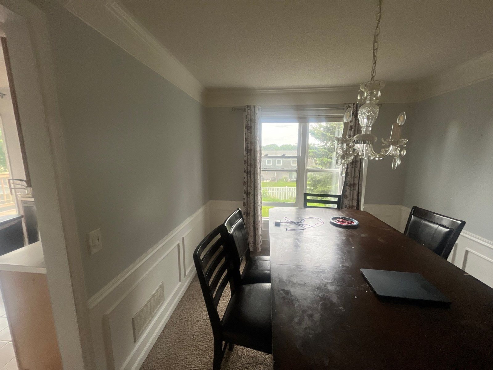 Dining room with a table, chandelier, and a wall with a window next to a patio door