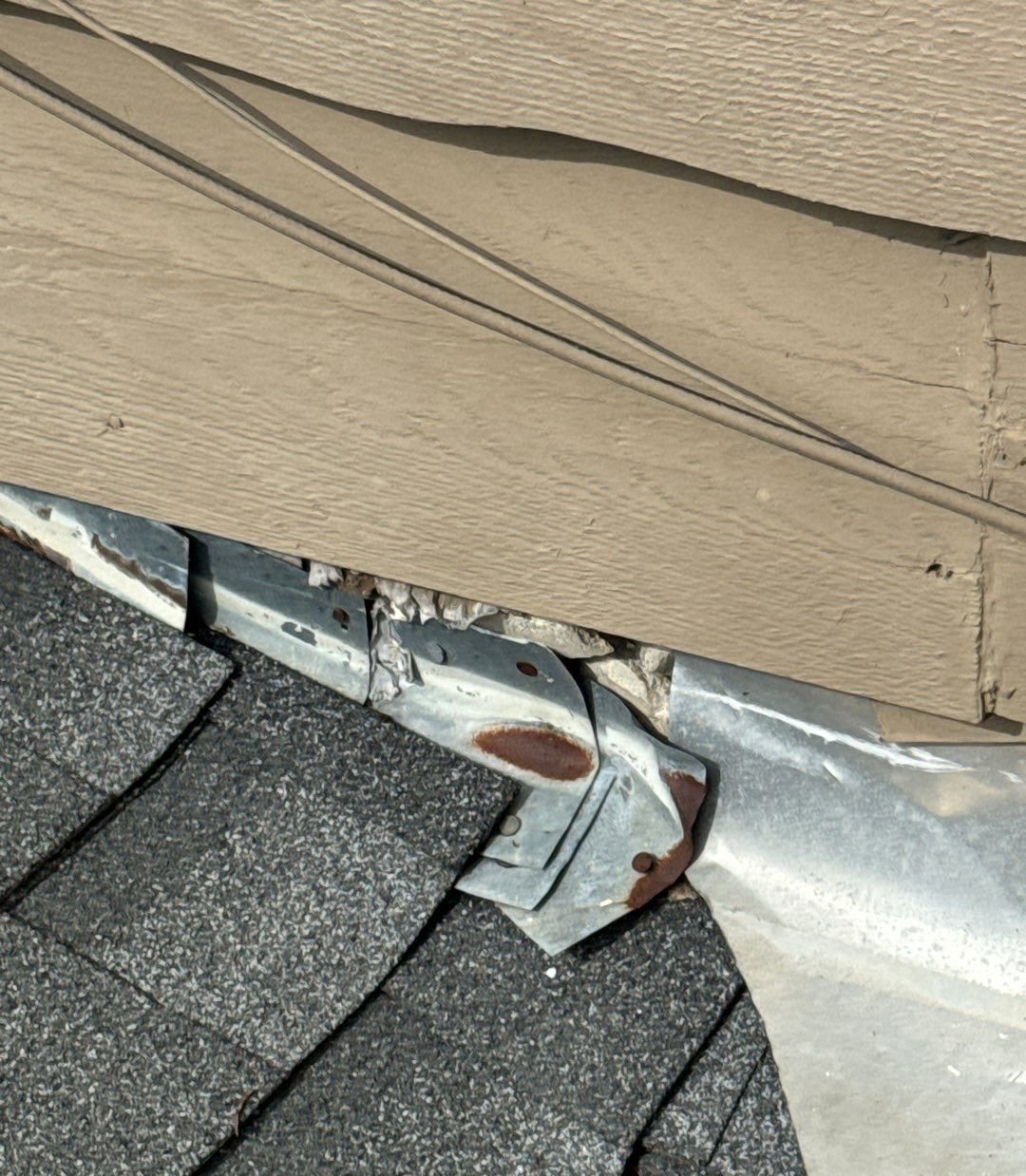 Step flashing where a shingle roof meets siding, bent and disturbed by a previous repair attempt