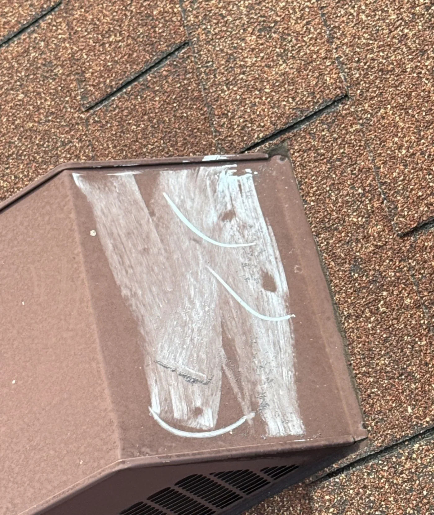 Brown aluminum roof vent with white chalk rubbed across the top and three small round dents circled
