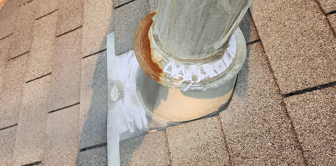 Vent pipe coming through a shingle roof with its flashing and sealant