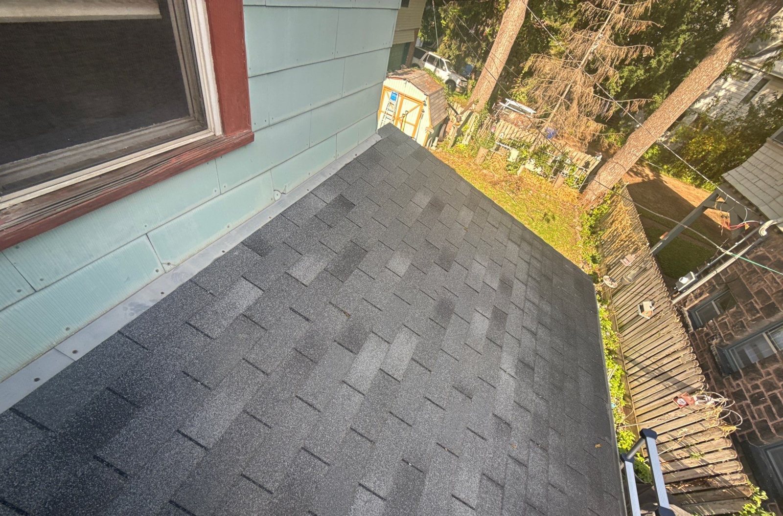 Shingle roof section running along a siding wall where the roof-to-wall flashing needs replacement