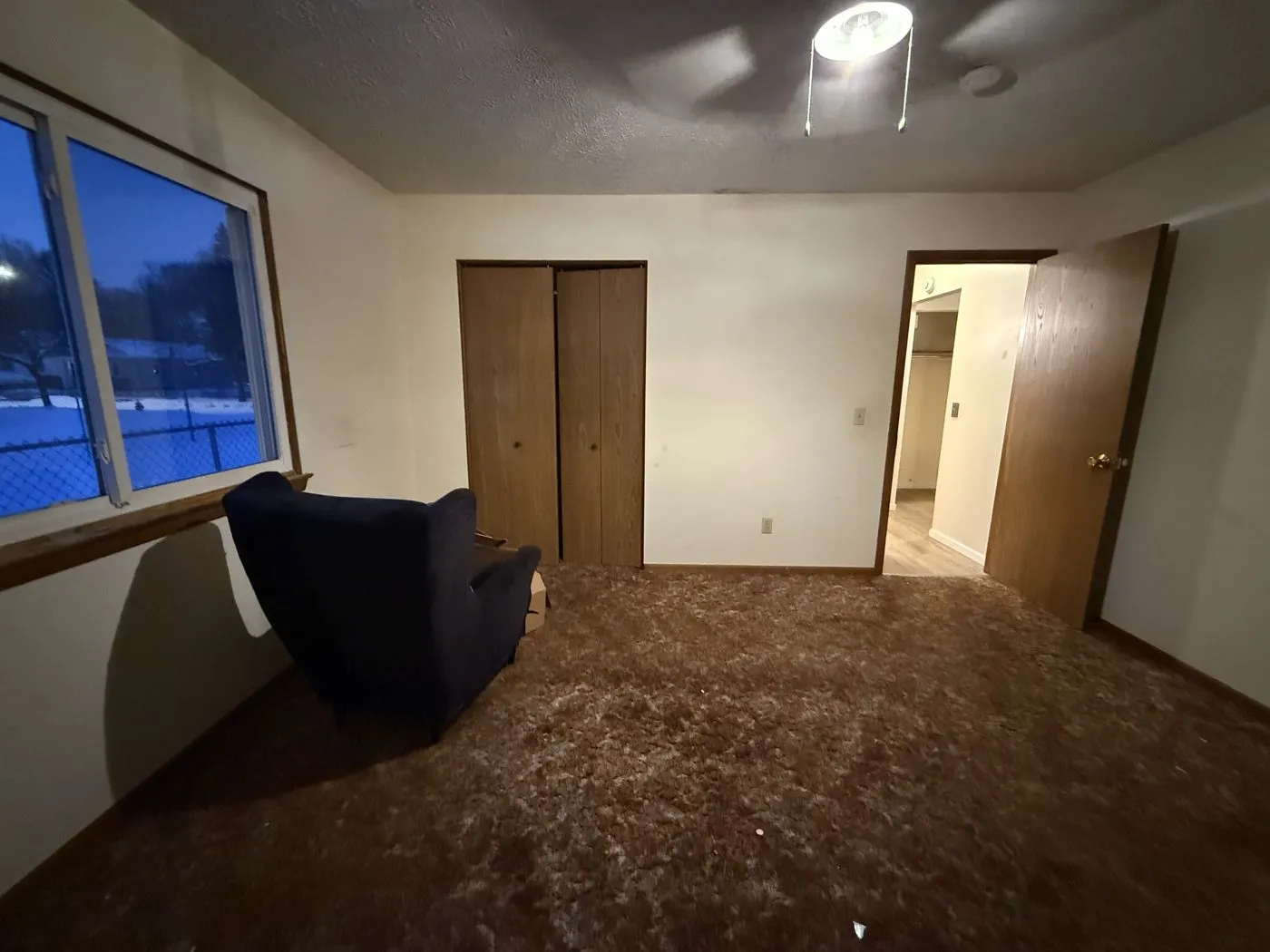 The same bedroom on possession day — worn shag carpet and leftover furniture