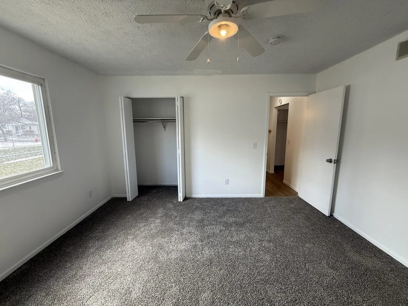 Bedroom after the turnover — new carpet, fresh paint and a new ceiling fan