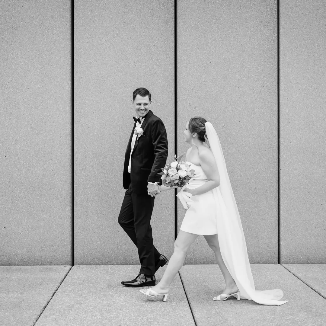 Black and white photo of a bride and groom walking together