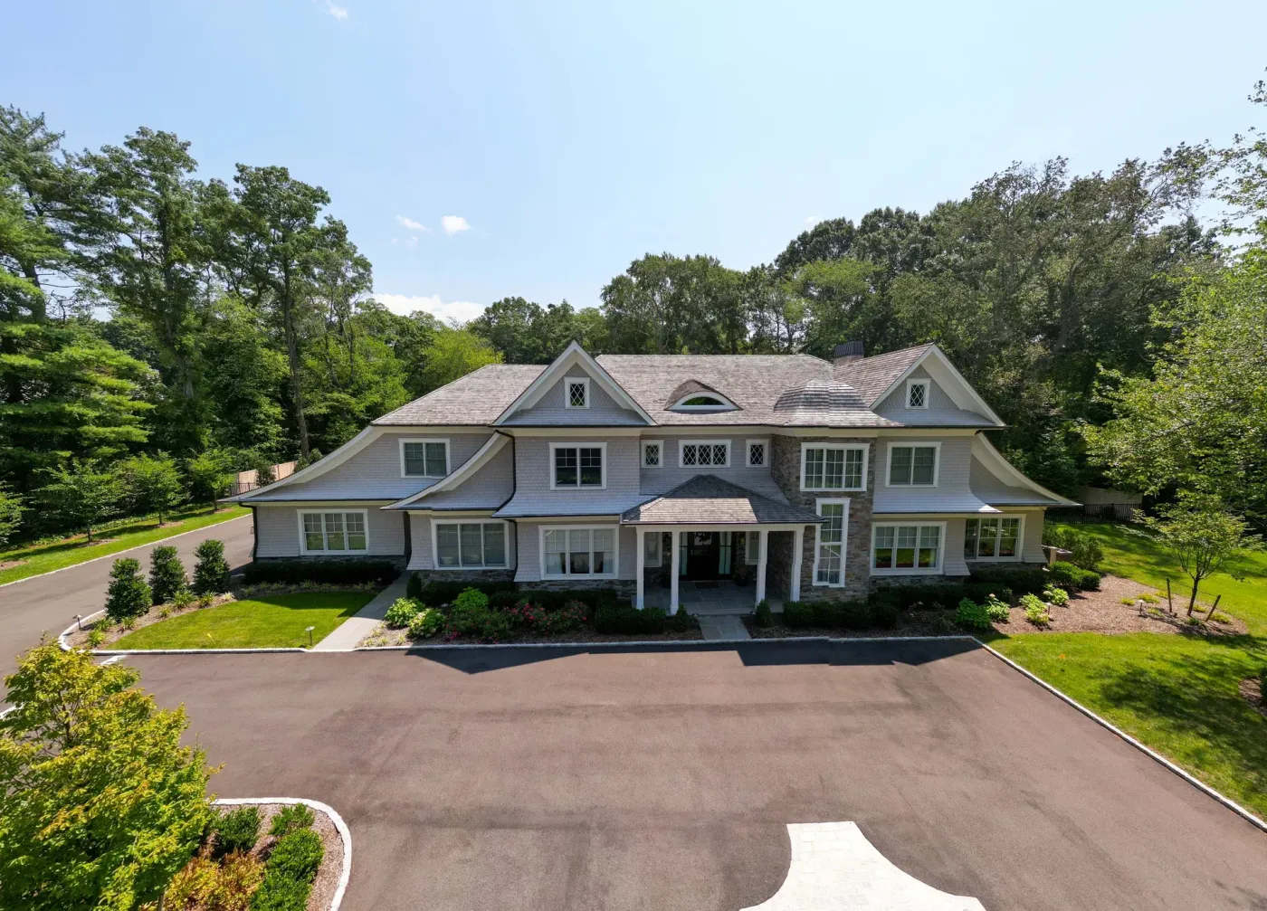 Brookville Cedar Estate, aerial view of the full front elevation - cedar shingle over a stone base, the drive and lawn in front