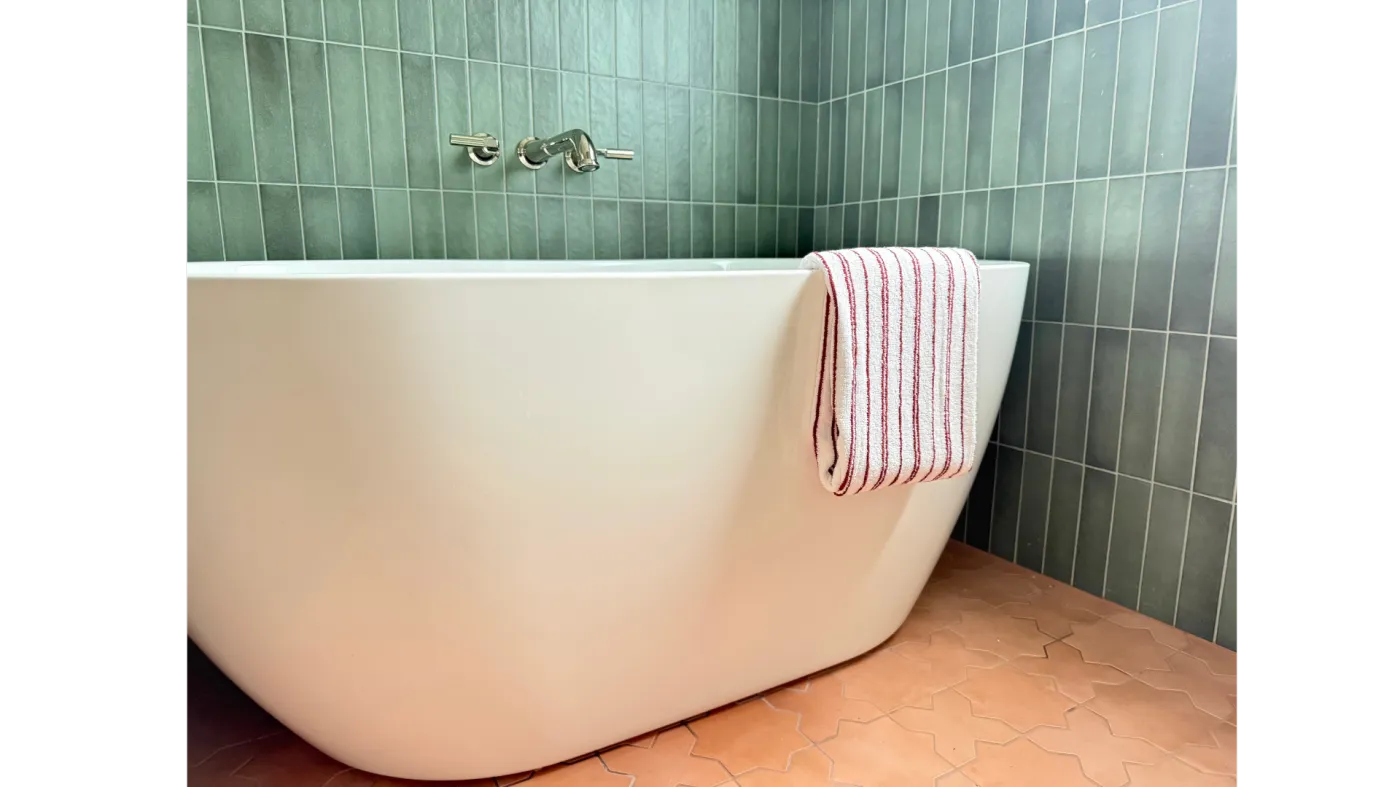 Freestanding soaking tub against sage green vertical tile in a recent Atlanta bathroom remodel