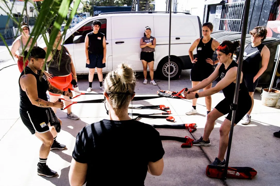 Members training with suspension straps in an outdoor class