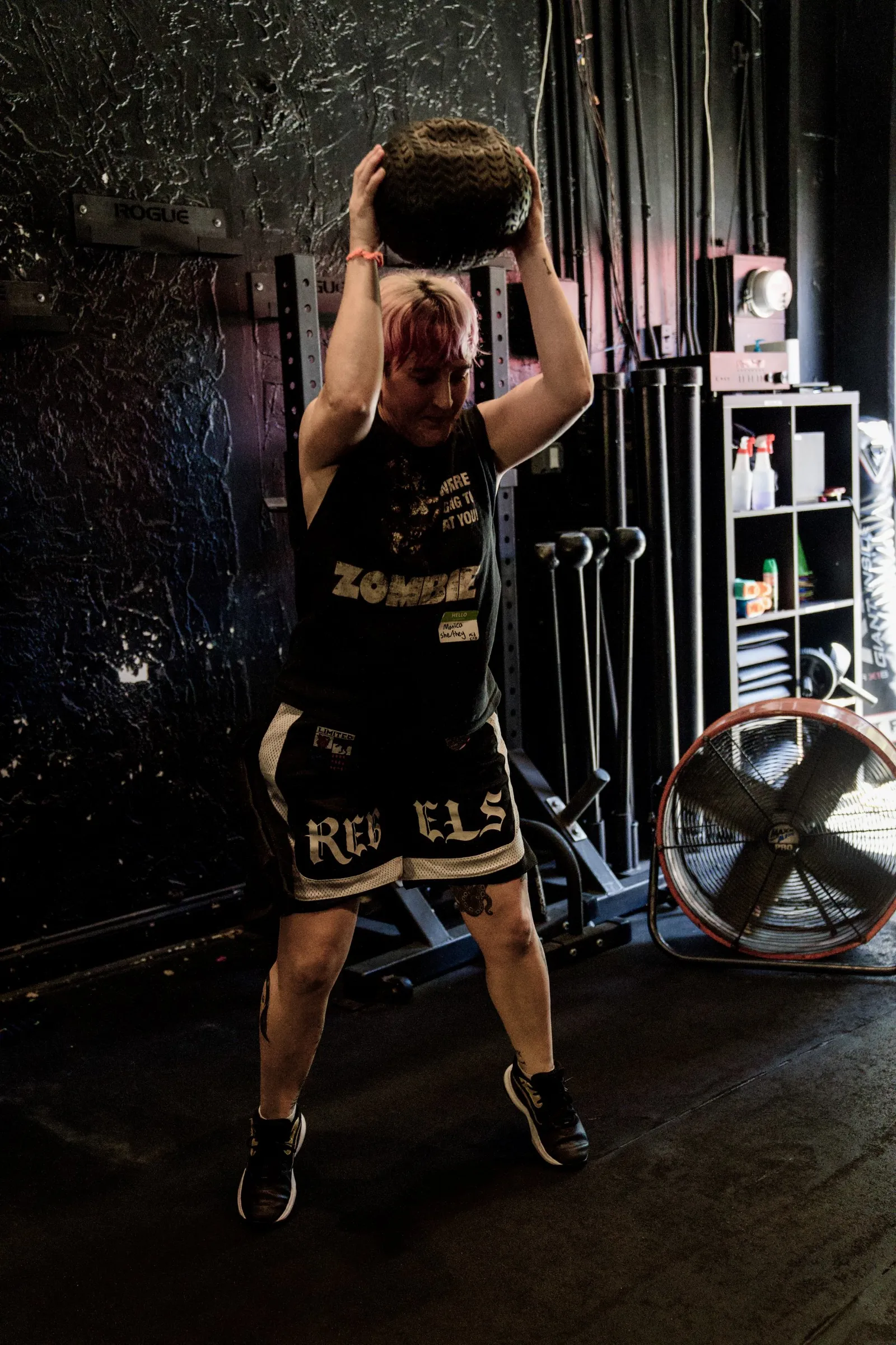 A member lifting a sandbag overhead during strength class at The Phoenix Effect in Los Angeles