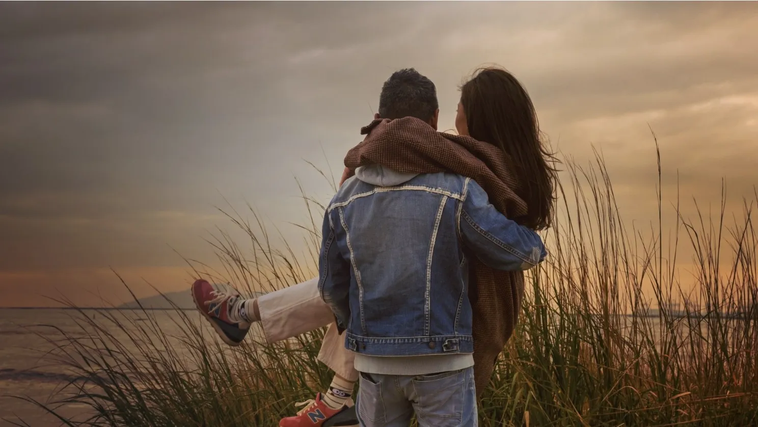A man carrying his partner through tall grass