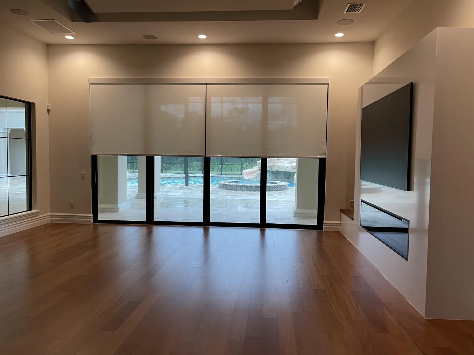 Roller shades lowered over sliding doors in a wide living room