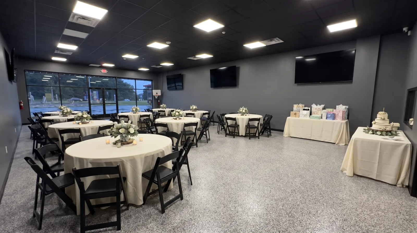 The Commons event room in Plains, PA set with round tables, cream linens and a cake table for an evening celebration