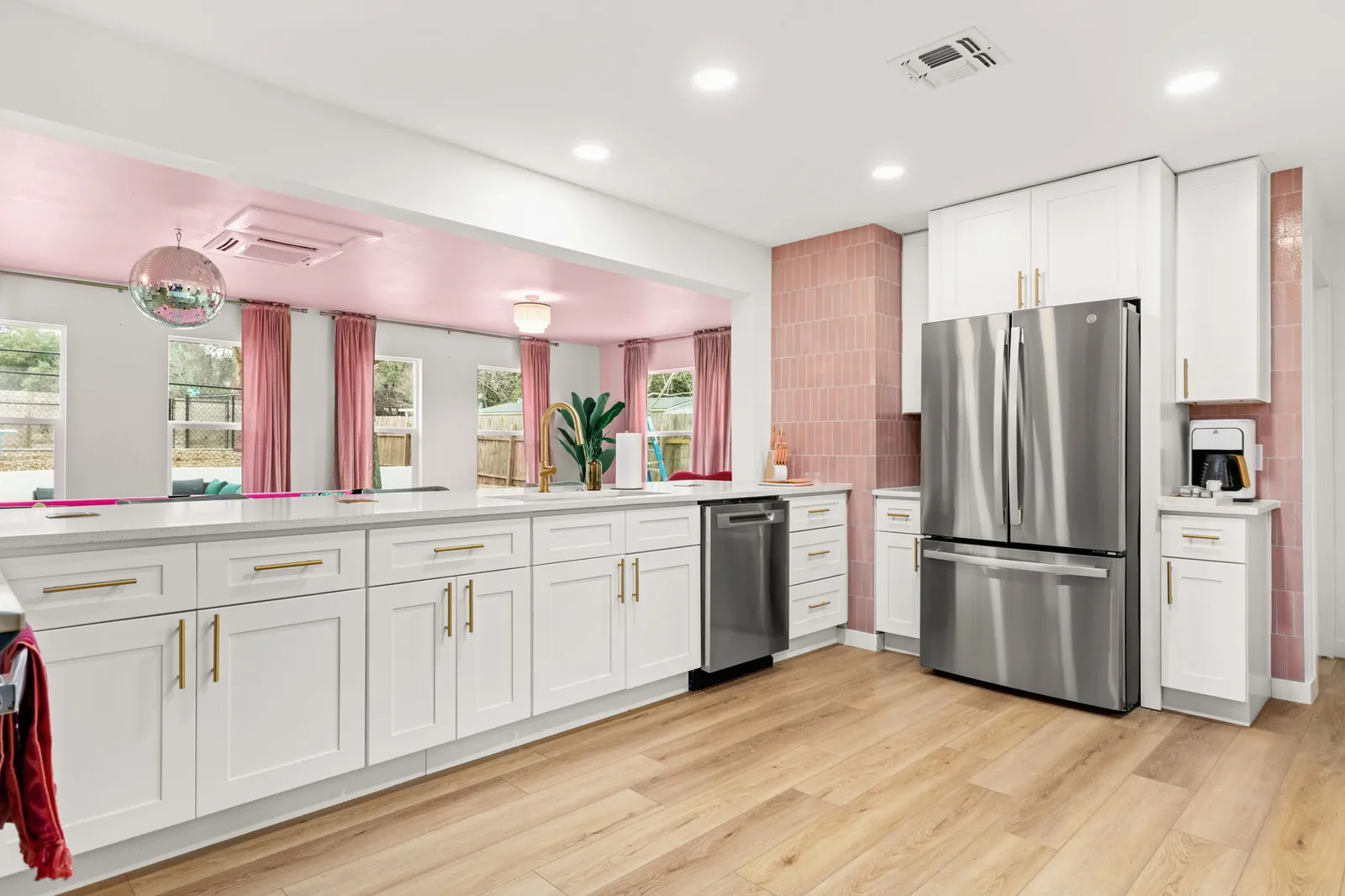 Kitchen with white shaker cabinets, pink tile and a pink-ceilinged breakfast nook