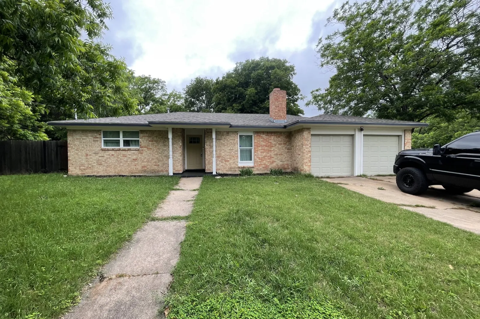 Exterior before: original tan brick, cracked walk and overgrown lawn