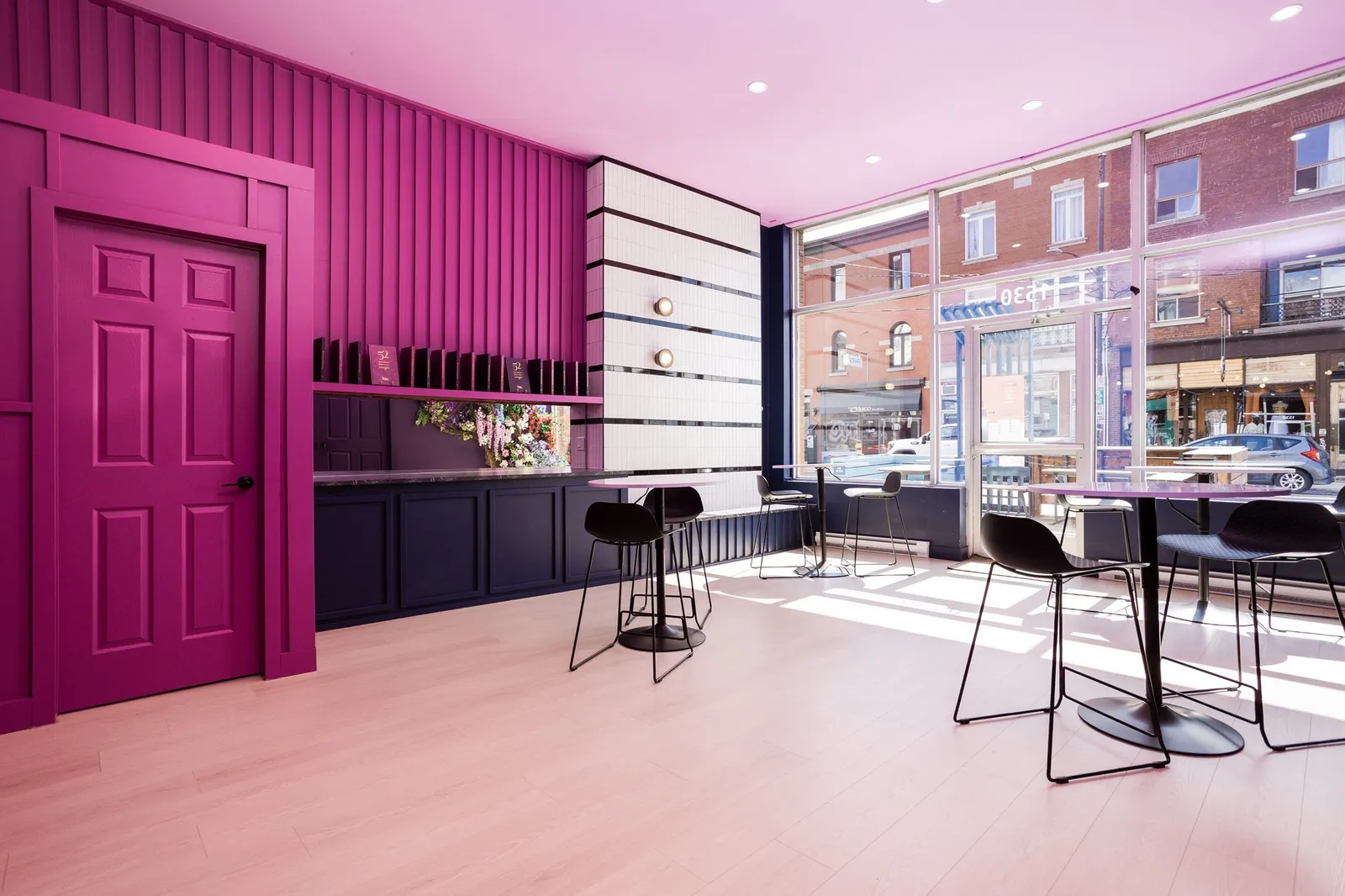 Espace bistro rose et aubergine baigné de lumière, vue sur la rue Notre-Dame