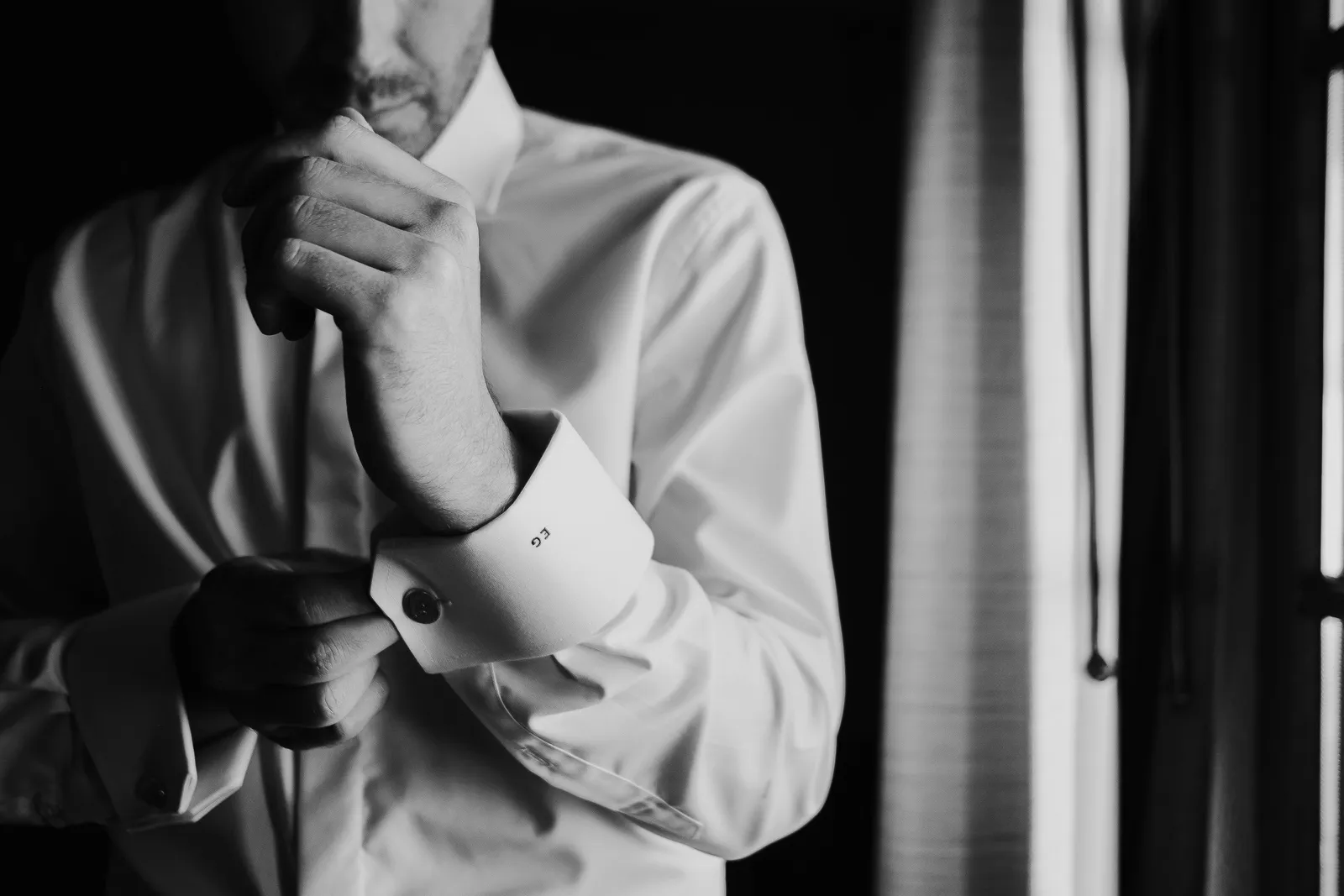 Un uomo in camicia bianca si allaccia il polsino