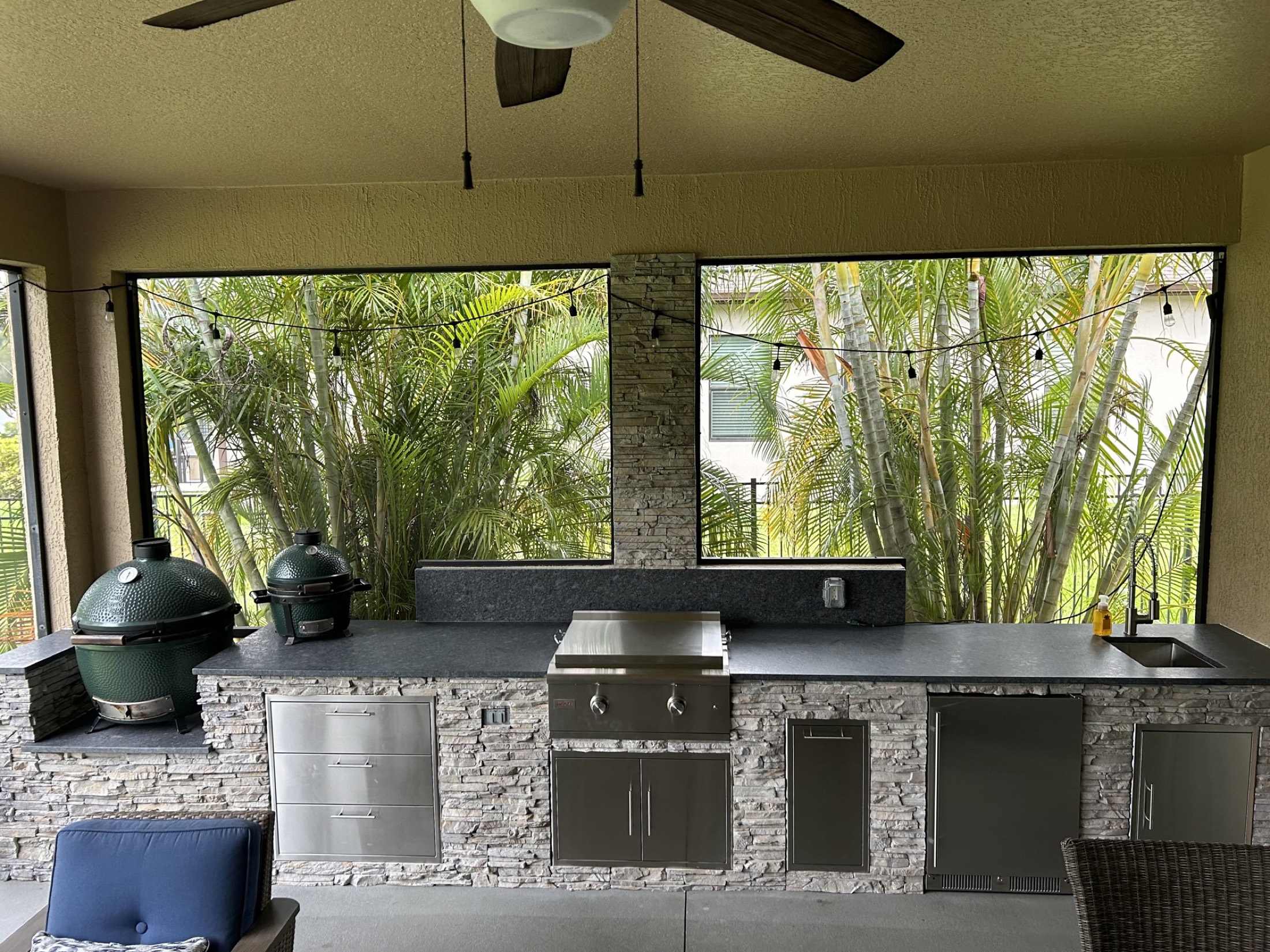 Custom outdoor kitchen with bar seating and LED lighting at twilight, built by Endless Summer in Melbourne, Florida