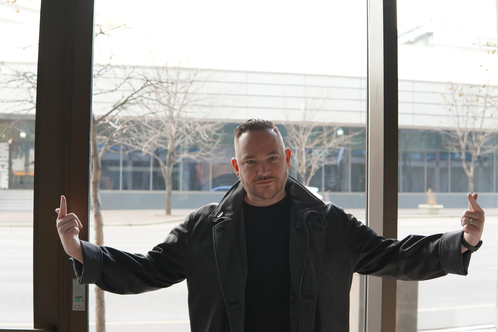 Adam Hagaman standing at a window with his arms spread