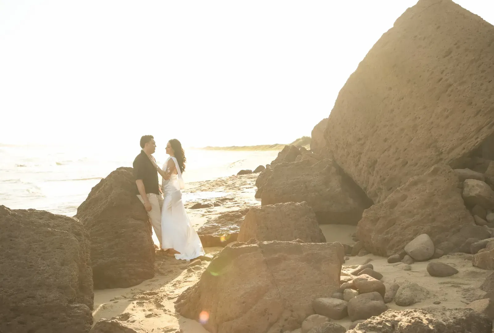 Isamar y Brian abrazados entre las rocas, con el sol de frente