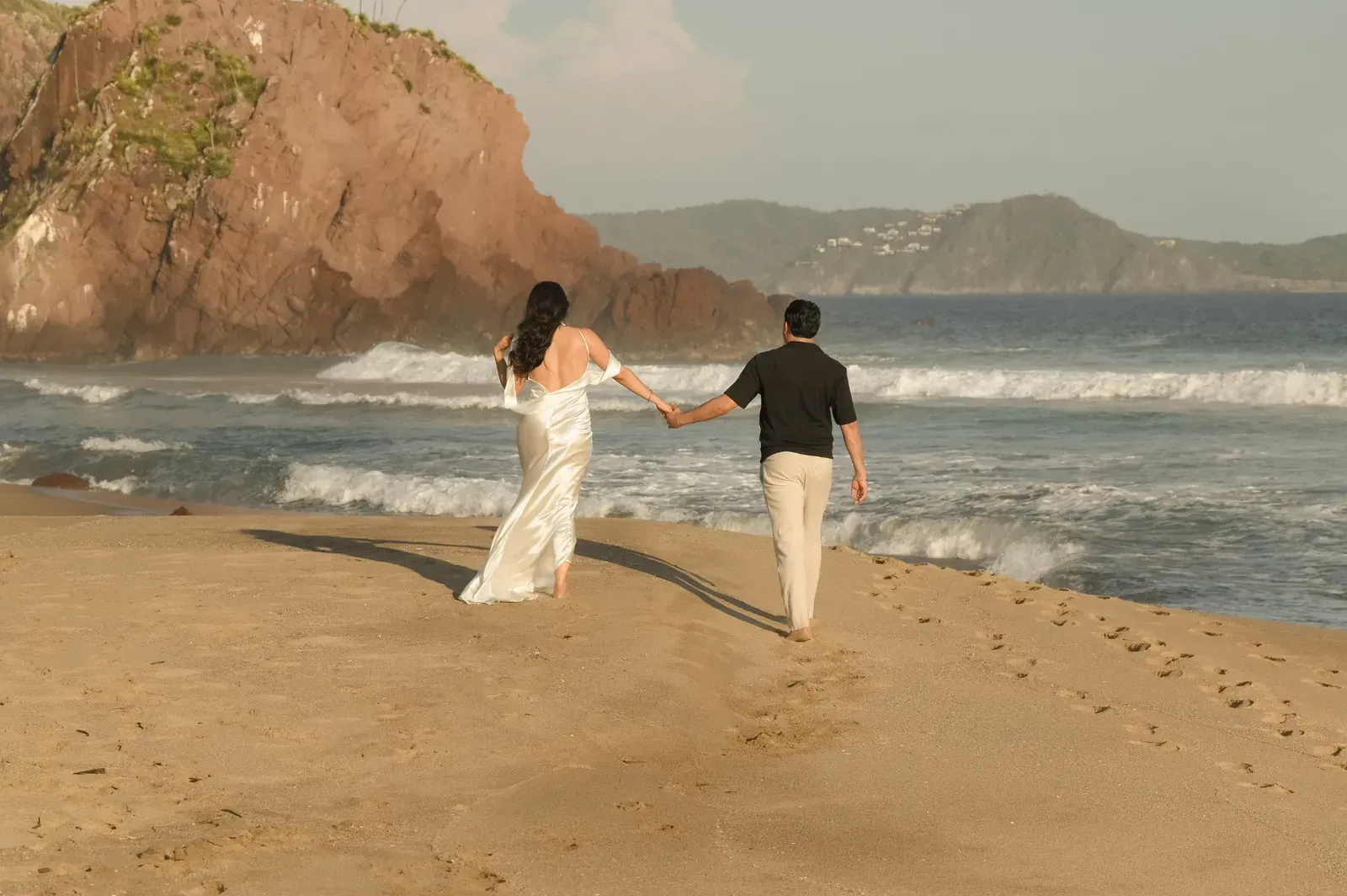 Isamar y Brian caminan de la mano hacia el mar