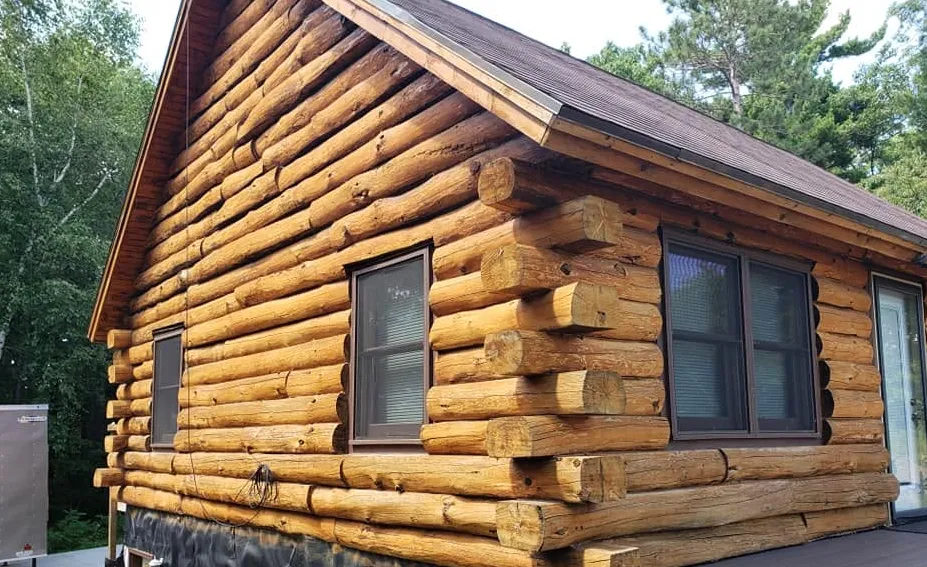 Before: Weathered log cabin exterior before staining
