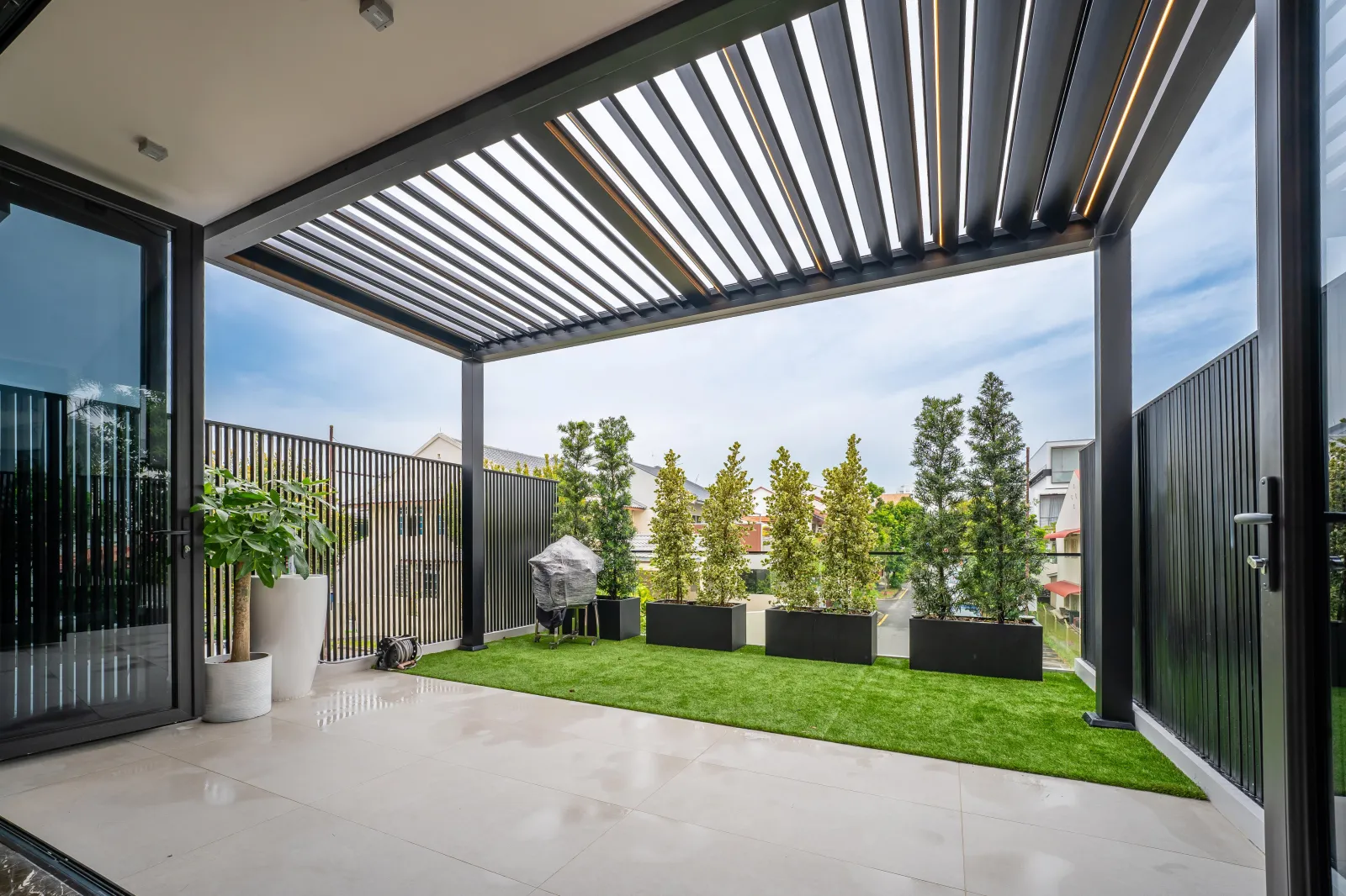 Motorised louvre pergola over a lawn