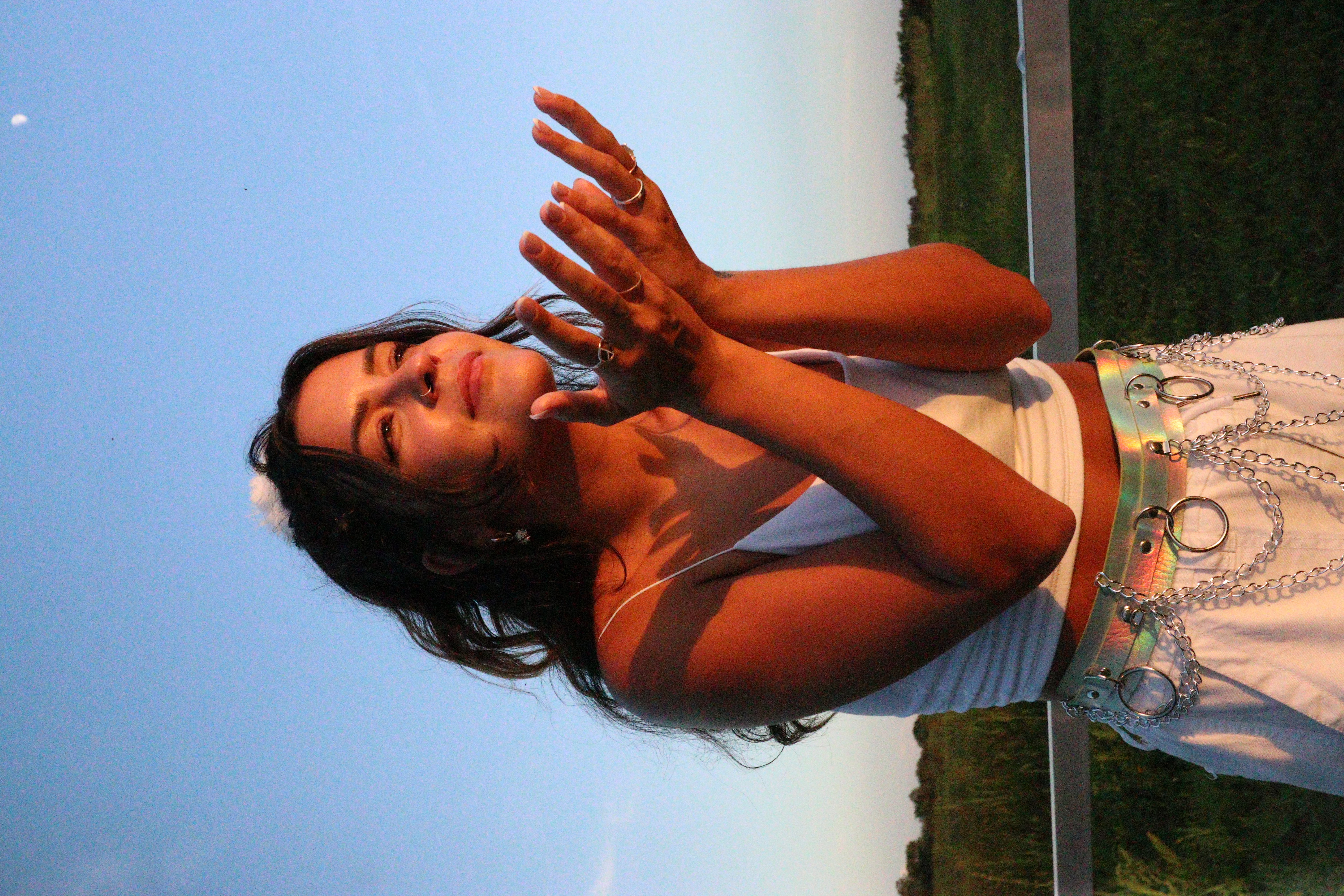 Madi under an open sky, hands cupped toward the light