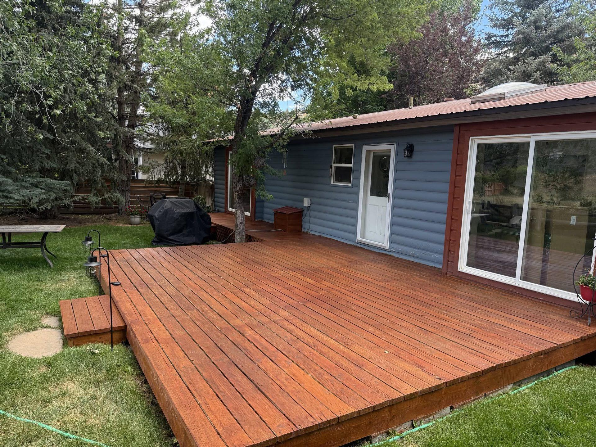 Large backyard deck freshly stained a warm cedar color with a step down to the lawn