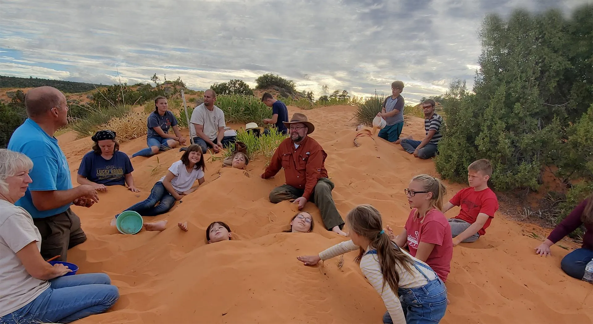 A TruthSeekers tour group exploring red sand dunes