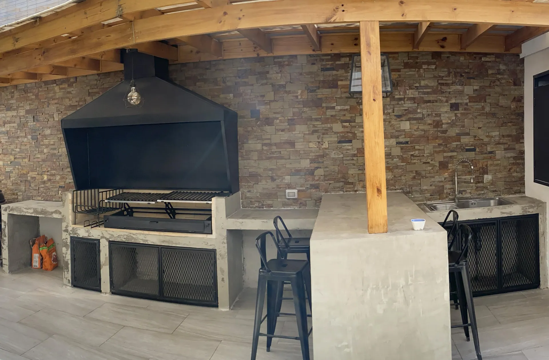 Quincho con pérgola de madera curva, parrilla y barra de hormigón construido por Marvar