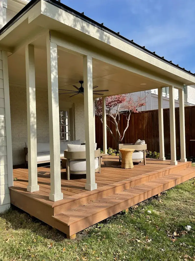 Covered back porch with a wood deck floor and outdoor furniture next to a cedar fence