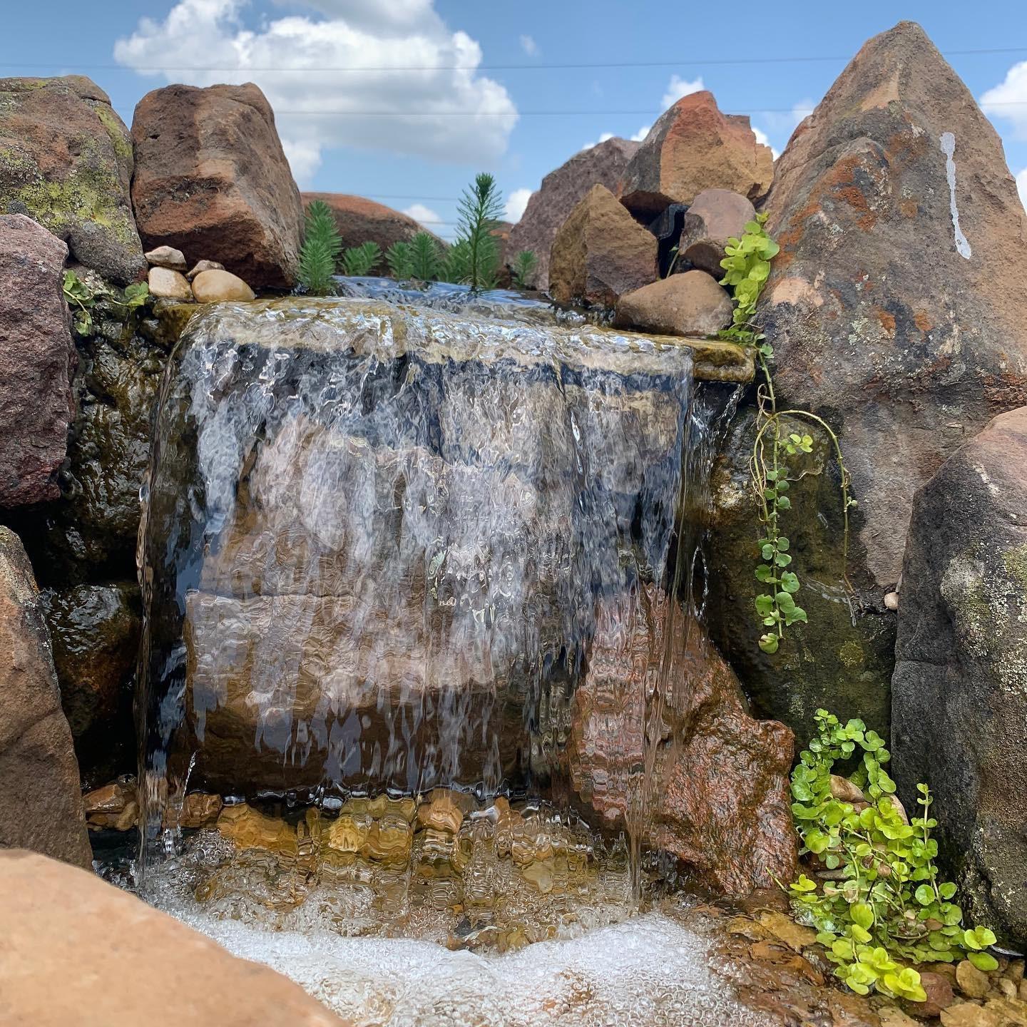 Sheet waterfall pouring off a single boulder