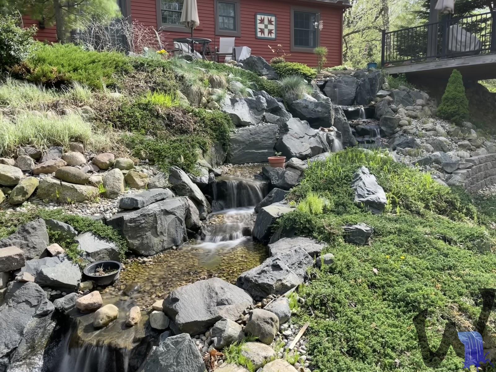 Hillside waterfall and stream through a sloped yard