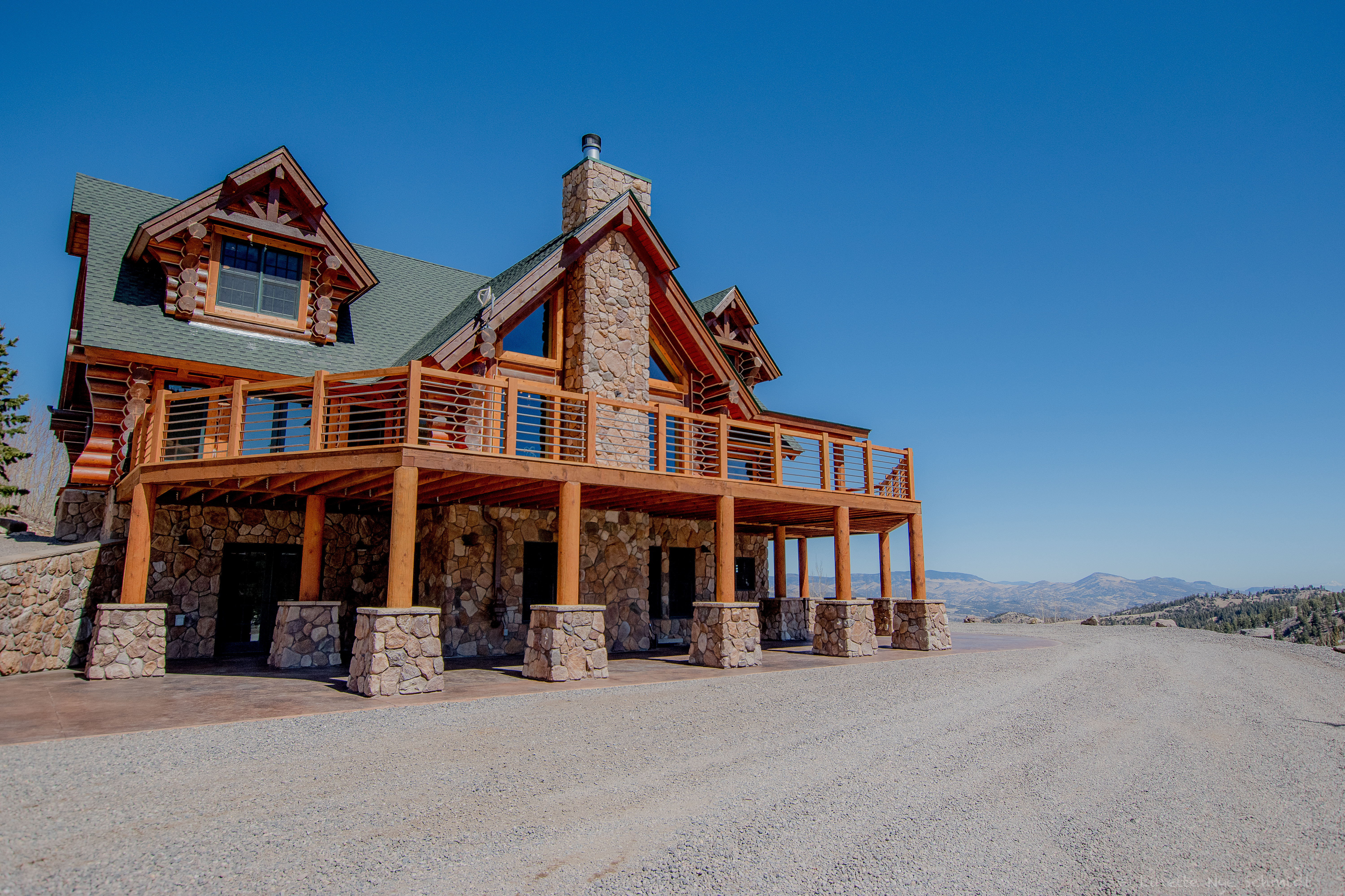 Elk Court log home with stone chimney, broad decks and mountain views