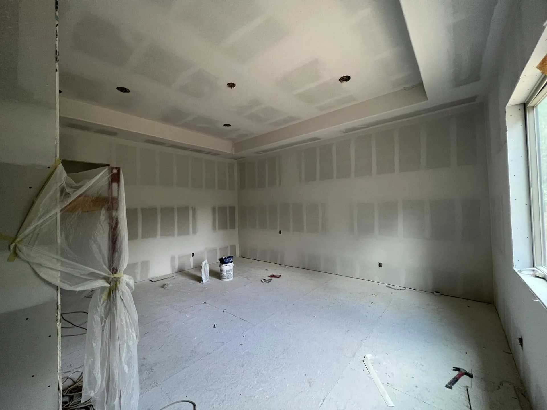 Room with a tray ceiling and freshly finished drywall seams