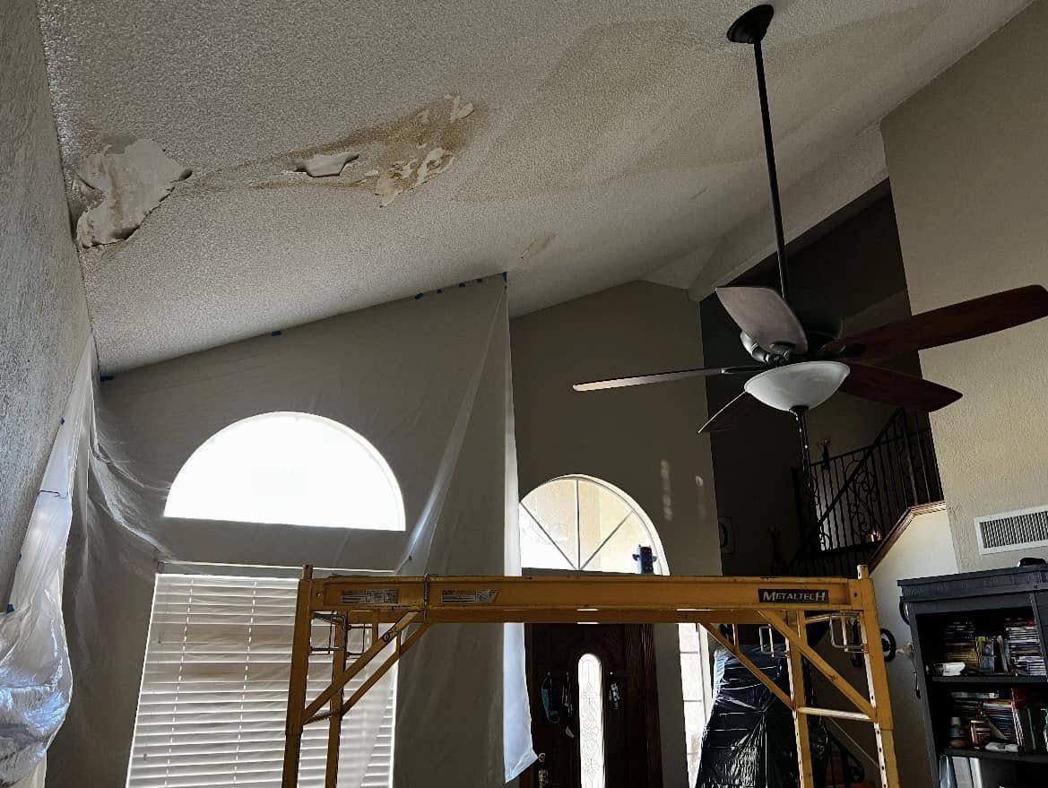 Popcorn ceiling being scraped in a living room with scaffolding