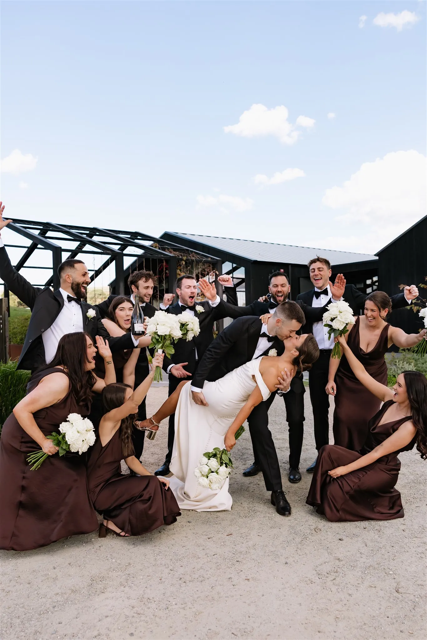 Bridal party cheering under a dark timber pavilion