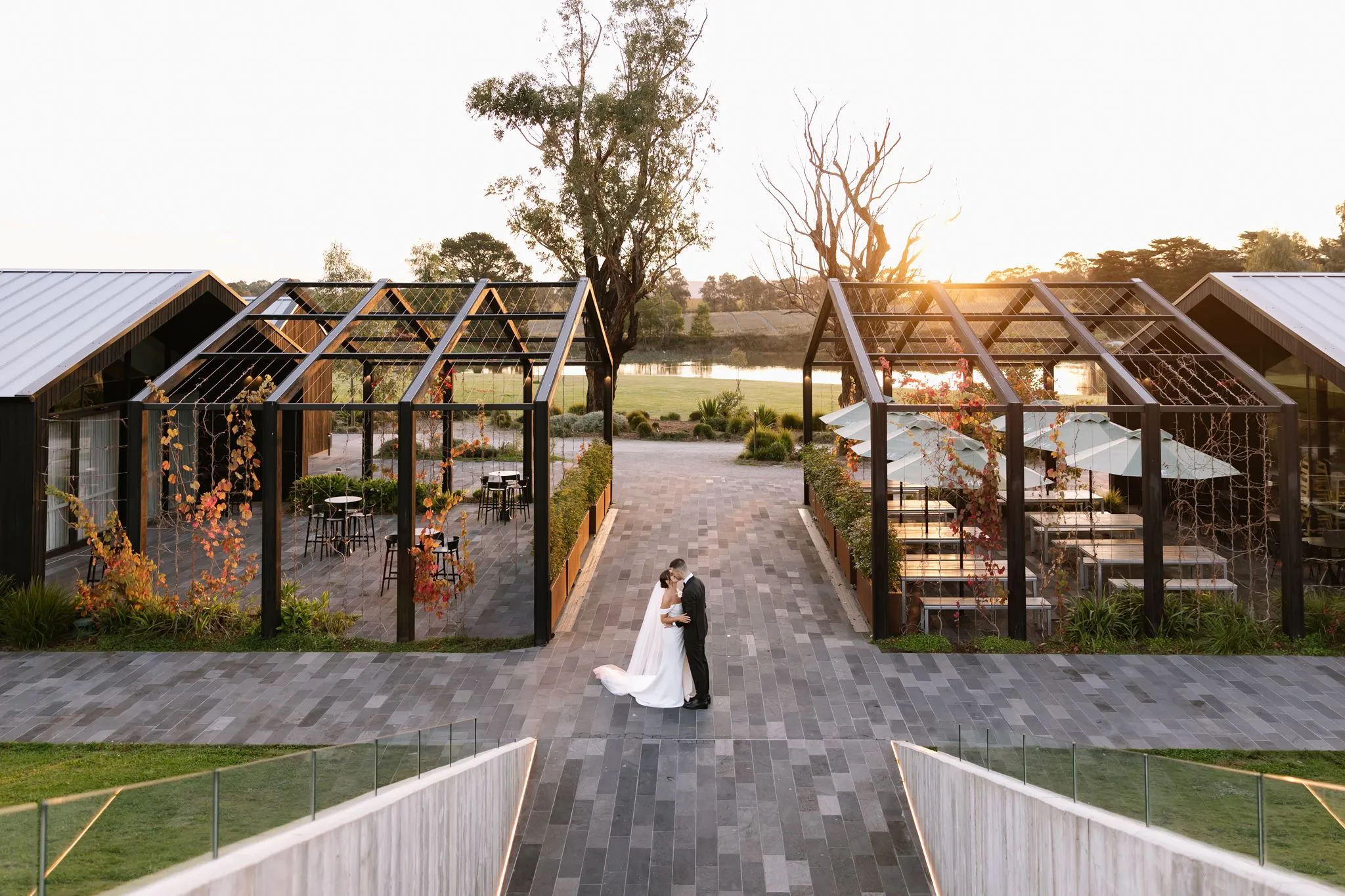 Couple at the end of a paved walkway between dark pavilions at sunset