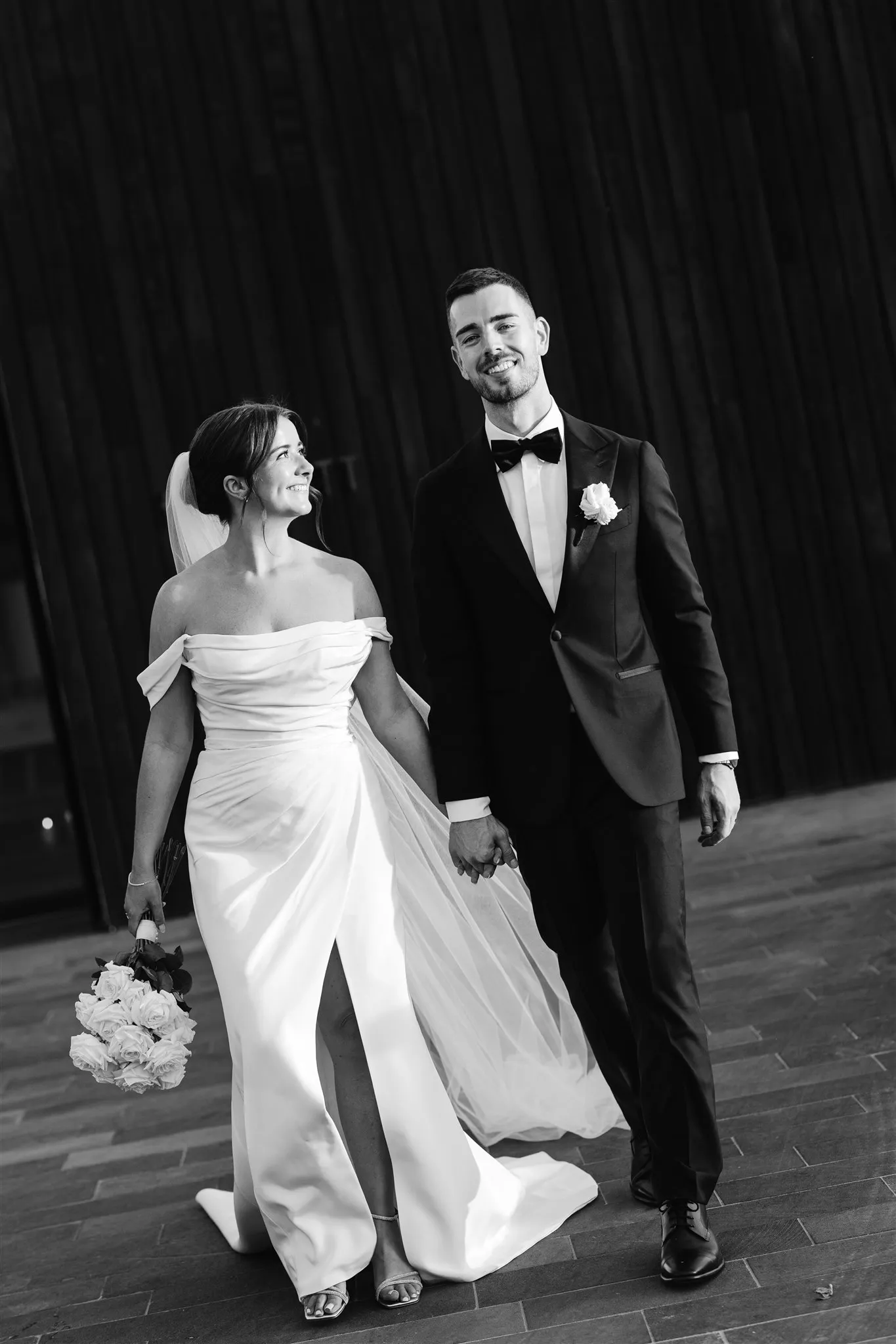 Bride and groom walking out into the night in black and white