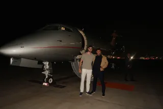 Two people beside a private jet at night